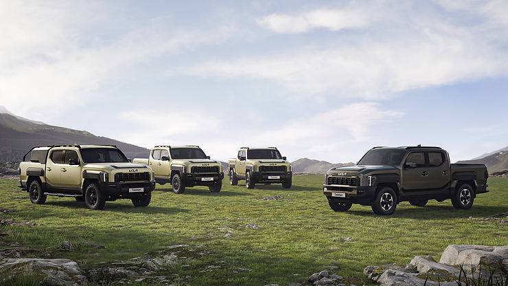 Tres camionetas Kia Tasman estacionadas en un prado frente a montañas nevadas